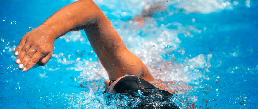 Nageur en pleine action durant un stage de triathlon axé sur la natation, démontrant technique et puissance dans l'eau.